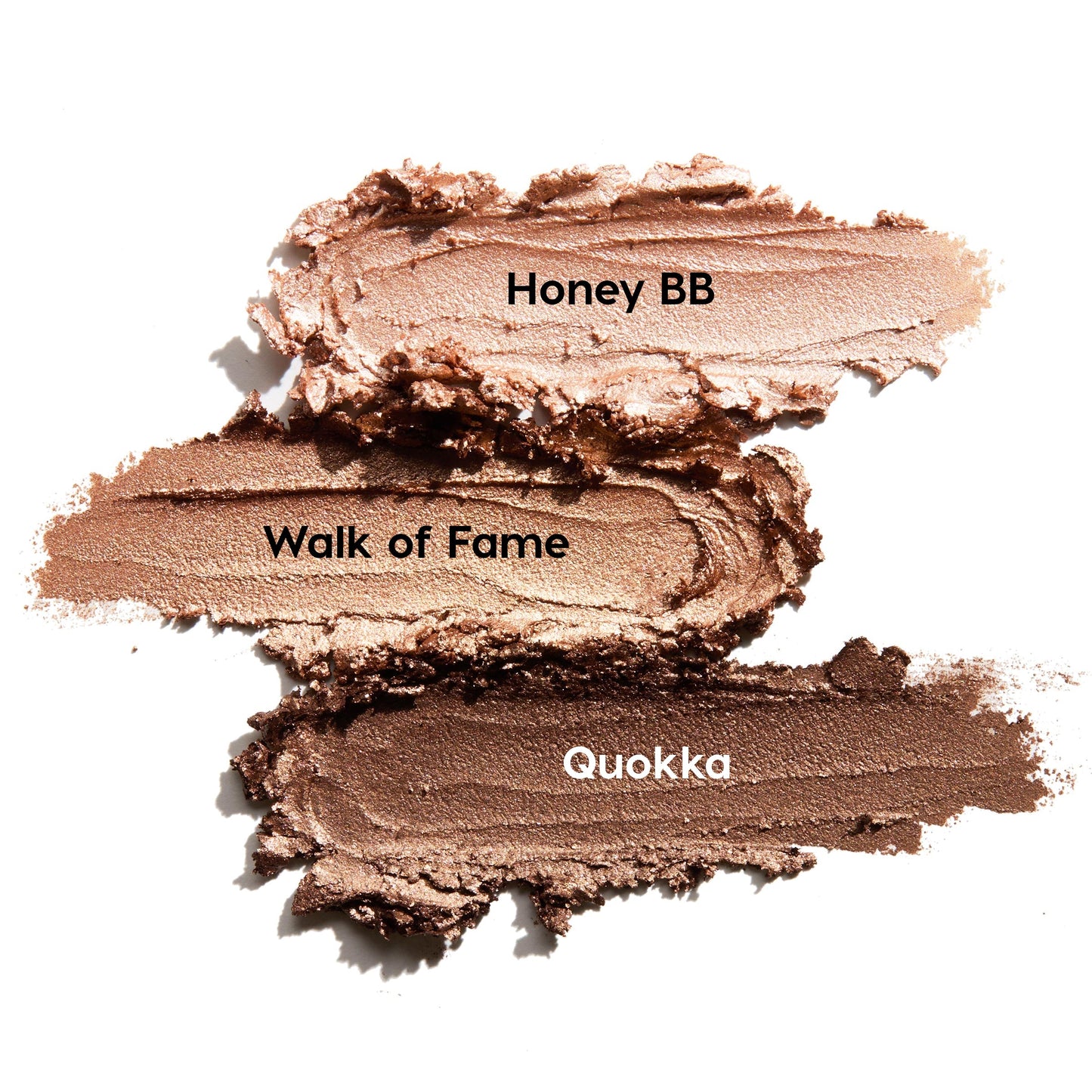 ColourPop Shadow Stix Shimmering Golds swatches display three creamy metallic strokes on a white background - Honey BB (champagne), Walk of Fame (warm gold), and Quokka (deep bronze) - smeared to showcase shimmer and blendable payoff.